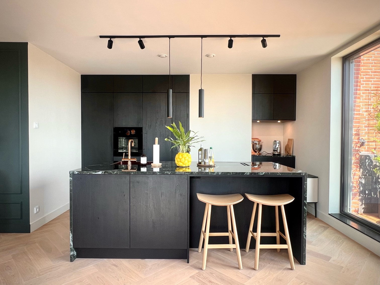 zwarte 1-fase railverlichting boven een kookeiland met hanglampen voor Hue