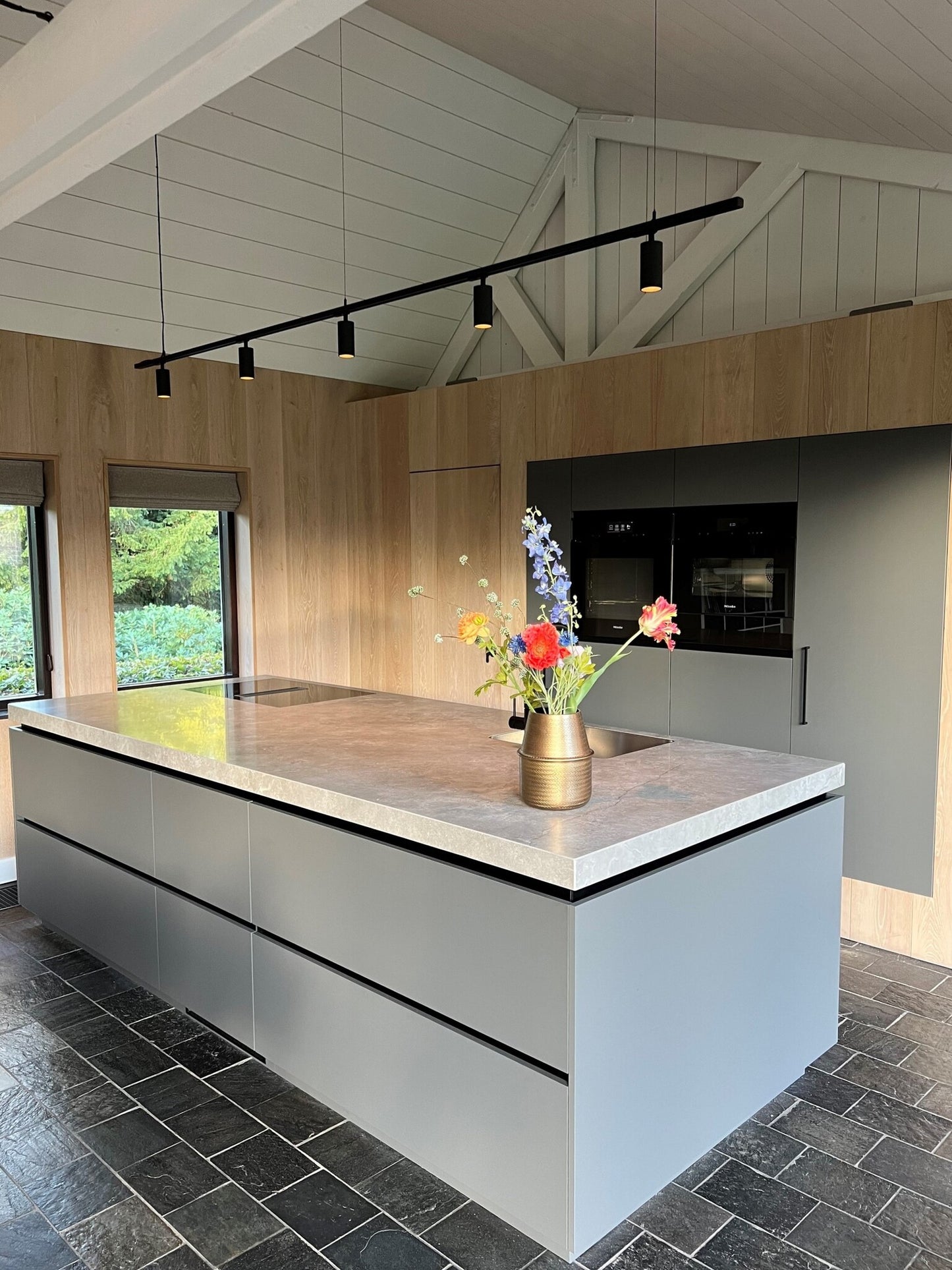 Zwevende railverlichting boven een kookeiland in een woning me puntdak