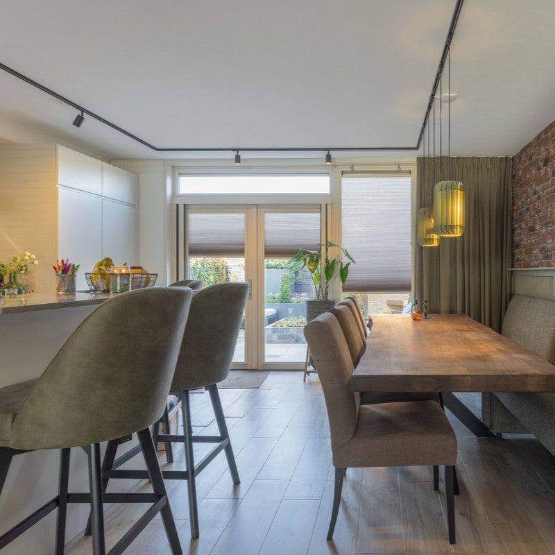 zwarte railverlichting boven kookeiland en eettafel gevoed vanuit één stroompunt