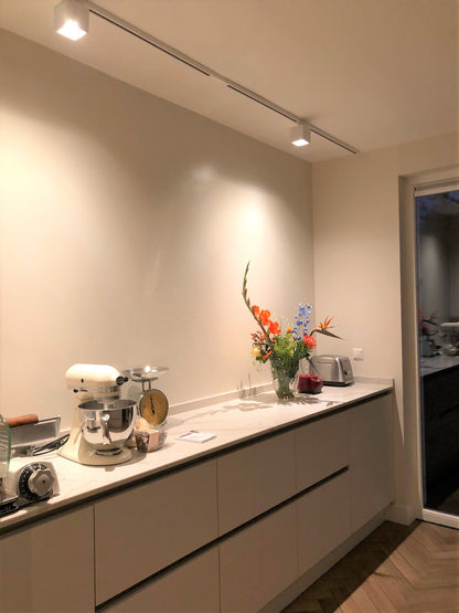 Witte railverlichting met kubusvormige KUBY GU10 spots in een modern interieur.